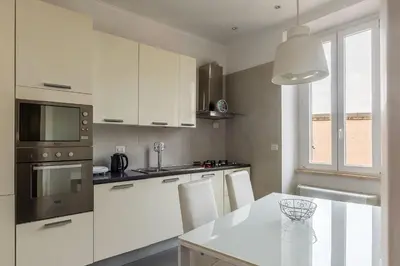 a kitchen with white cabinets and a table with chairs at GuestHost - Trastevere Station Bright Apartment with Terrace in Rome