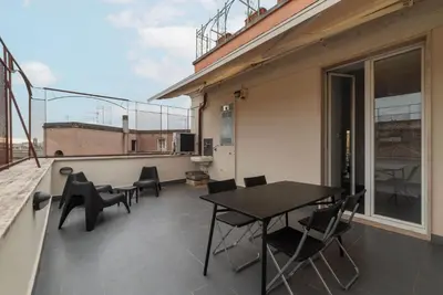a patio with a table and chairs on a balcony at GuestHost - Trastevere Station Bright Apartment with Terrace in Rome