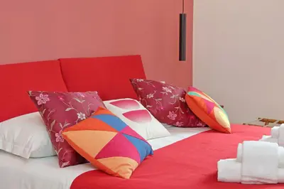 a red couch with colorful pillows on a red blanket at Scipioni2 in Rome