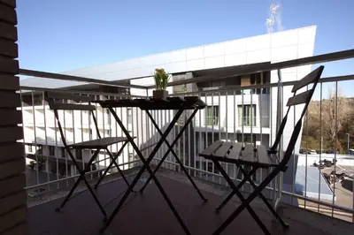 a table and chairs on a balcony with a building at Vigna Clara 2BR Holiday House in Rome