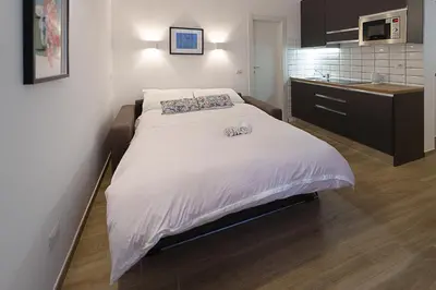 a bedroom with a large white bed and a kitchen at Casa Cesari in Rome