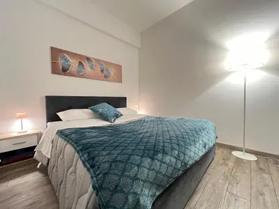 a bedroom with a bed with a blue blanket and a lamp at Sweet Home Acaia - San Giovanni in Rome