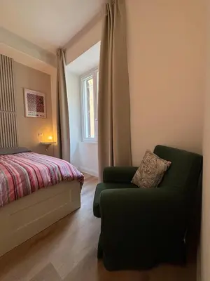 a bedroom with a bed and a chair and a window at Ilia12 home in Rome
