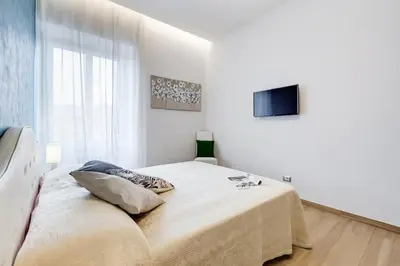 a white bedroom with a bed and a television at Vatican Brothers in Rome