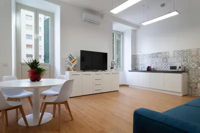 a white living room with a table and a tv at Studio Piramide in Rome