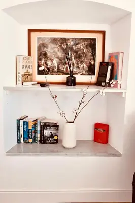 a shelf with books and a vase on a wall at Caesar's Nest in Rome