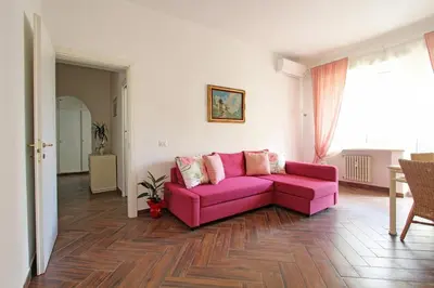 a pink couch in a living room with a wooden floor at A casa di Chloe - Ponte Milvio in Rome
