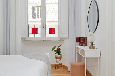 a white bedroom with a bed and a mirror at TreasureRome Adriana Charme 4BR in Rome