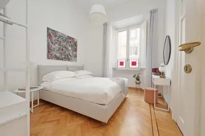 a white bedroom with a bed and a mirror at TreasureRome Adriana Charme 4BR in Rome