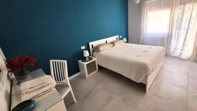 a bedroom with a white bed and a blue wall at Nuovissimo appartamento zona Vaticano Aurelio in Rome
