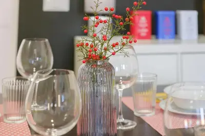 a vase with red berries in it on a table with wine glasses at Rome Urban Retreat - Metro A in Rome