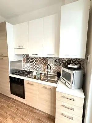 a kitchen with white cabinets and a sink and a microwave at Happy House with private garden in Rome