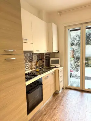 a kitchen with white cabinets and a stove top oven at Happy House with private garden in Rome