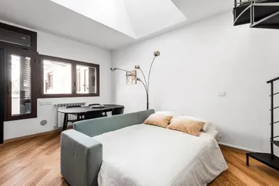 a white bedroom with a bed and a table at The Spiral Way - Trastevere apartment with large private terrace in Rome