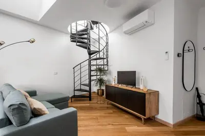 a living room with a blue couch and a spiral staircase at The Spiral Way - Trastevere apartment with large private terrace in Rome