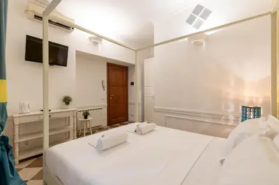 a white bedroom with a bed and a television at Domus 15 - Guest House in Rome