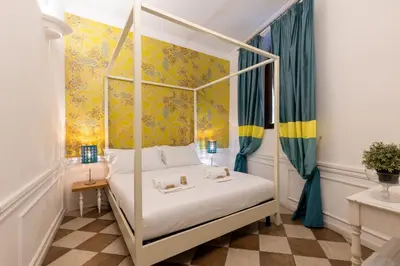 a bedroom with a four poster bed with yellow wallpaper at Domus 15 - Guest House in Rome