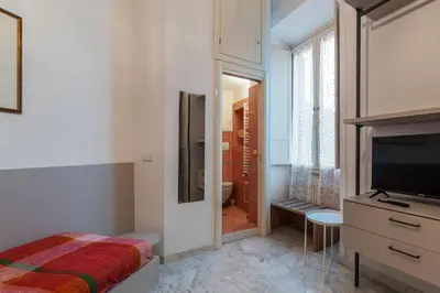 a bedroom with a bed and a television and a bathroom at GuestHost - Zia Pina's Apartment in Rome