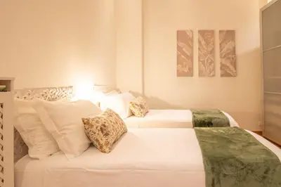 two beds in a bedroom with white sheets and pillows at A casa di Carlo Roma Vaticano in Rome