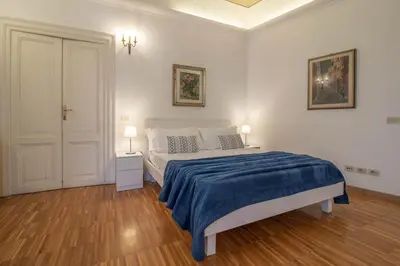 a white bedroom with a bed with a blue blanket at Casa Nicalandro Roma Centro in Rome