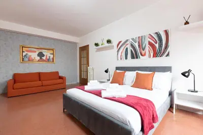 a bedroom with a large bed and a orange couch at Domvs Clavdia - 7min to Colosseum by Metro, Station under apt, Roma, 6pax, A-C in Rome