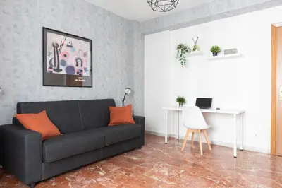 a living room with a black couch and orange pillows at Domvs Clavdia - 7min to Colosseum by Metro, Station under apt, Roma, 6pax, A-C in Rome
