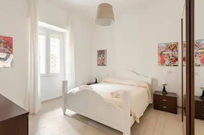 a white bedroom with a white bed and a window at Casa Polly in Rome