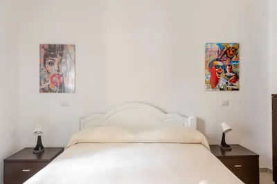 a bedroom with a white bed with two pictures on the wall at Casa Polly in Rome