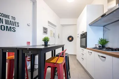 a kitchen with a black table and red chairs at Roman Waves Room - 2 MIN Metro Marconi - 15 MIN Colosseo - A-C & WIFI in Rome