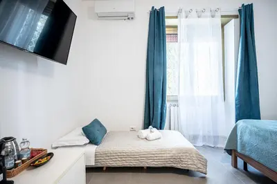a bedroom with a bed and a window with blue curtains at Roman Waves Room - 2 MIN Metro Marconi - 15 MIN Colosseo - A-C & WIFI in Rome