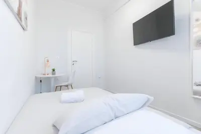 a white bedroom with a bed and a tv at 10 Min from Termini Sisters Cozy Rome Apartment in Rome
