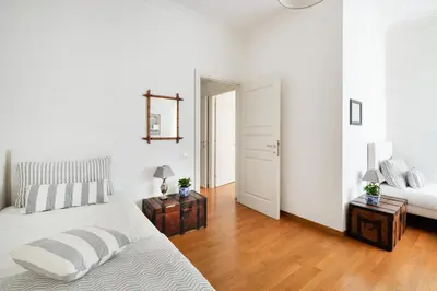 a white bedroom with a bed and two tables with lamps at La Dimora dell'Antiquario in Rome