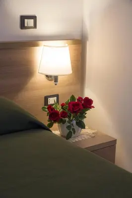 a vase of red roses sitting on a table with a lamp at B&B Trastevere in Bed in Rome
