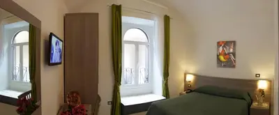 a bedroom with a green bed and two windows at B&B Trastevere in Bed in Rome