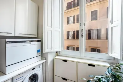 a kitchen with white cabinets and a washer and dryer at Your nest with wooden ceilings in Monti in Rome