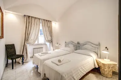 a white bedroom with two beds and a window at Casa Vacanze Crispi in Rome
