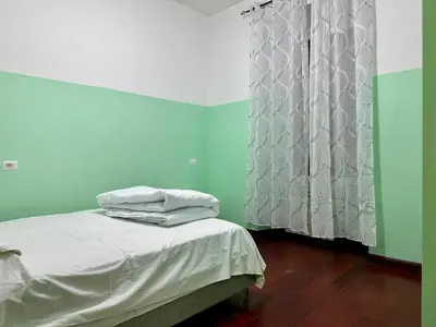 a bedroom with green walls and a bed with white sheets at Bellaroma Astréa apartment in Rome
