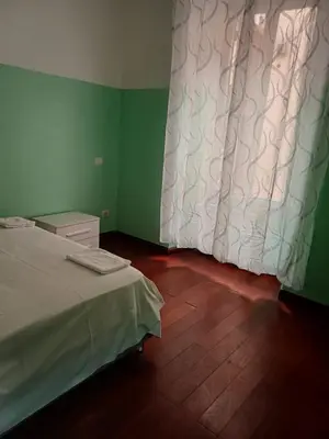a green room with a bed and a curtain at Bellaroma Astréa apartment in Rome
