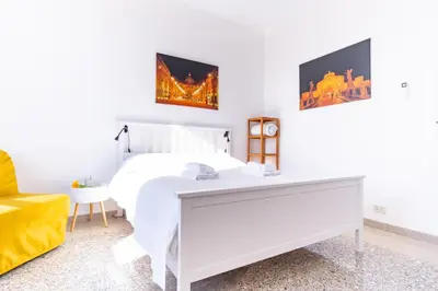 a white bedroom with a white bed and a yellow chair at Elegantis La Dolce Vista Apartment with private terrace and fantastic View in Rome