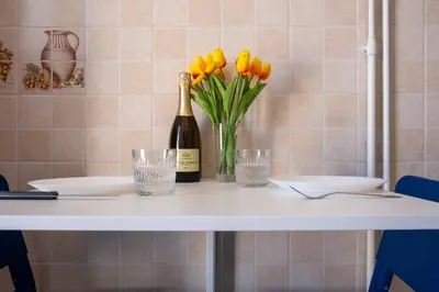 a table with a bottle of champagne and yellow tulips at Elegantis La Dolce Vista Apartment with private terrace and fantastic View in Rome