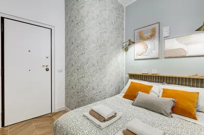 a white bedroom with a large bed with orange pillows at BDC - Love nest! Small but cozy in Rome