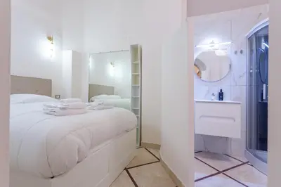 a white bedroom with a large bed and a bathroom at Oliviero - Piazza Navona Suite in Rome