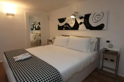 a bedroom with a white bed with black and white sheets at LHP Suite Roma Piazza del Popolo in Rome