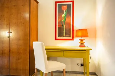 a desk with a white chair and a lamp at La Piccola Retró , urban color and comfort in Rome