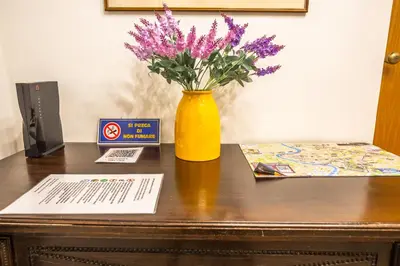 a yellow vase with purple flowers on top of a table at La Piccola Retró , urban color and comfort in Rome
