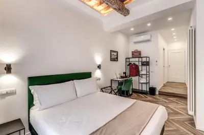 a bedroom with a white bed and a green headboard at Effe Luxury Rooms in Rome