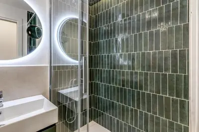a bathroom with a sink and a shower with green tiles at Effe Luxury Rooms in Rome