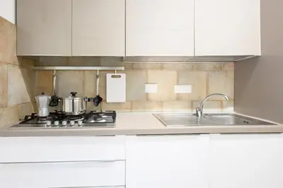 a kitchen with a sink and a stove and white cabinets at Prosper House in Rome