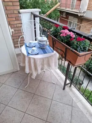 a balcony with a table and flowers on a balcony at Le chat bleu in Rome