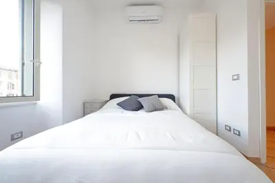 a white bedroom with a white bed with two pillows at Testaccio Sweet Holiday Apt in Rome